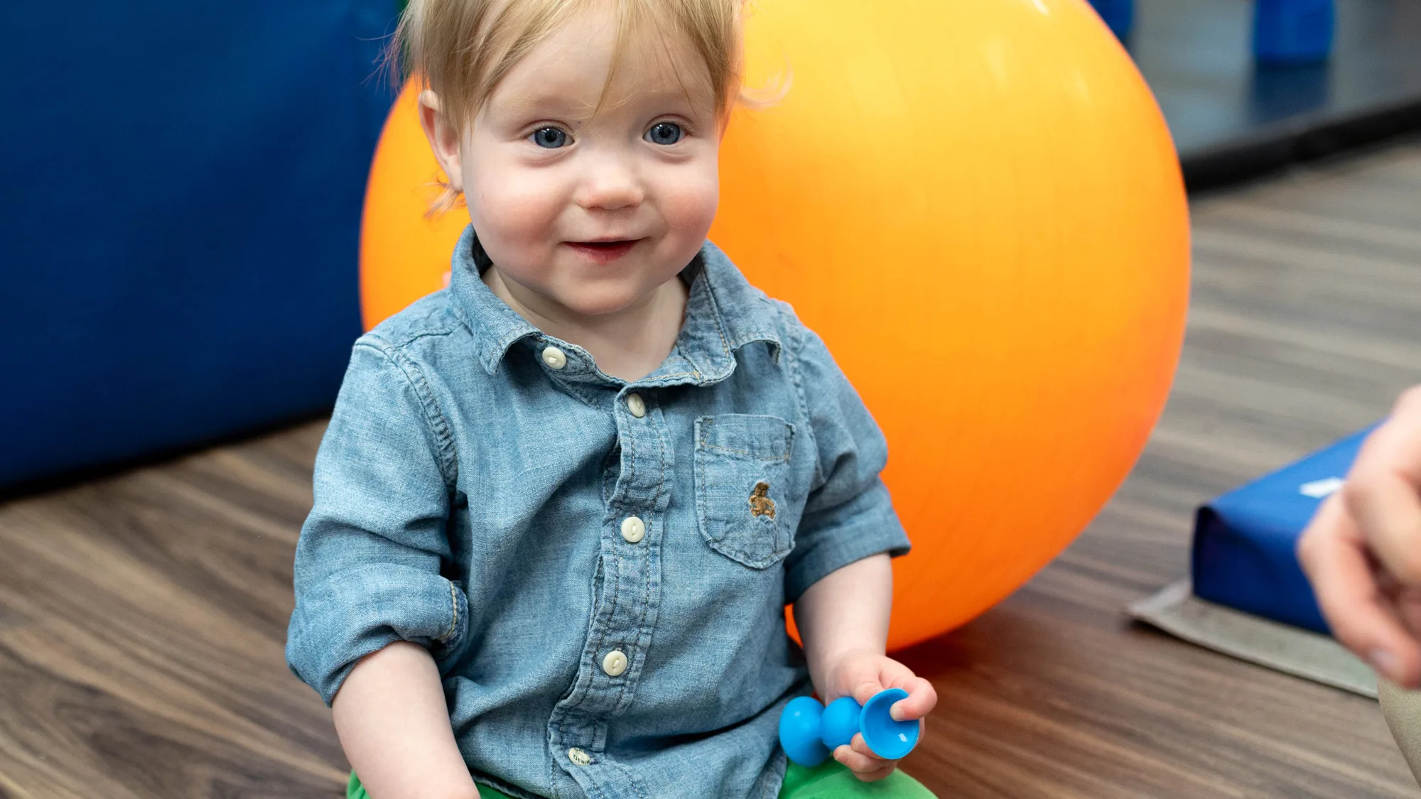 toddler with toy next to therapy ball