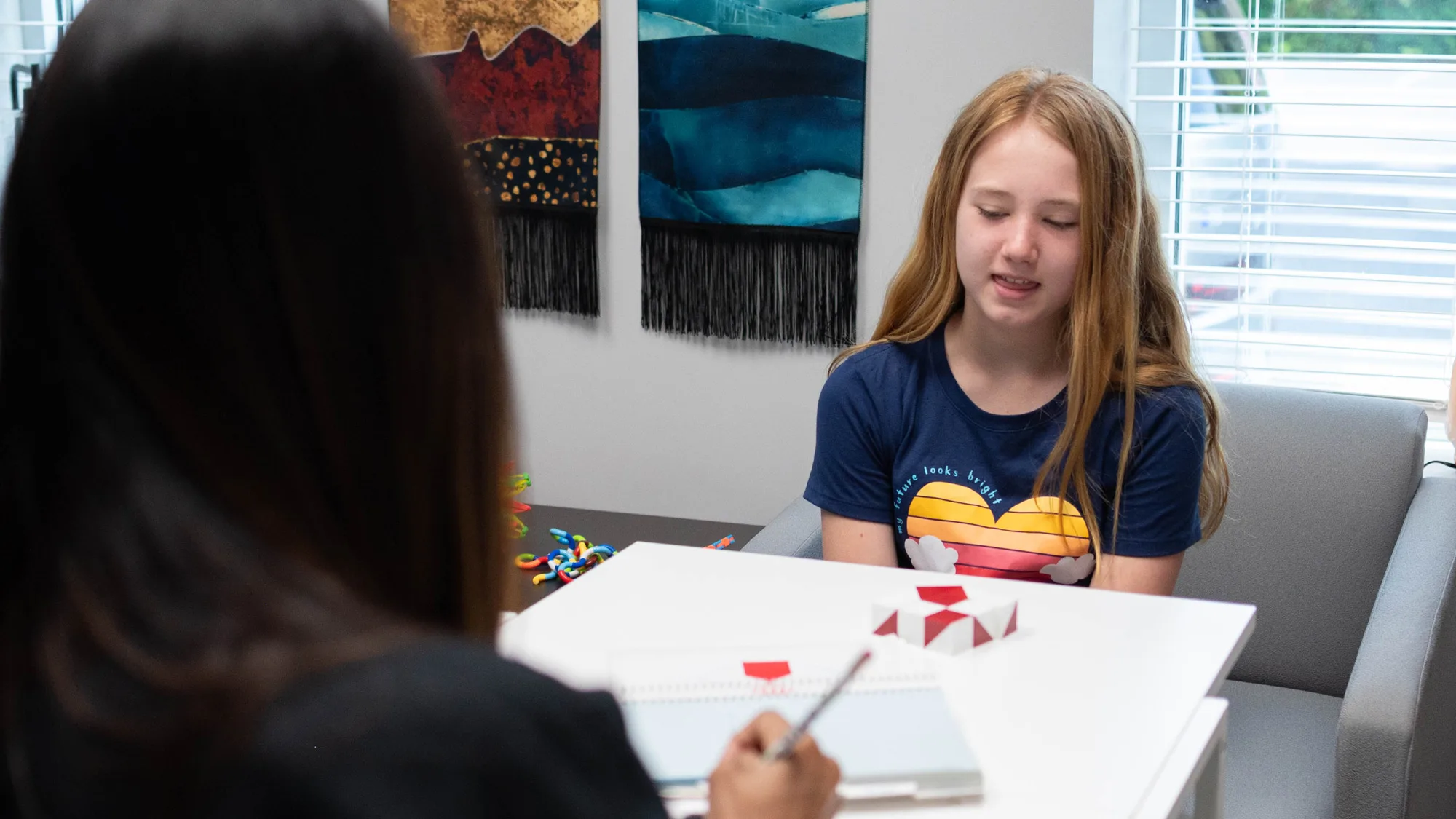 girl and therapist looking at shapes on table